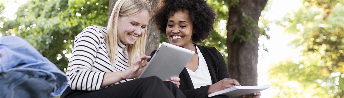 Två tjejer sitter och tittar i en tablet