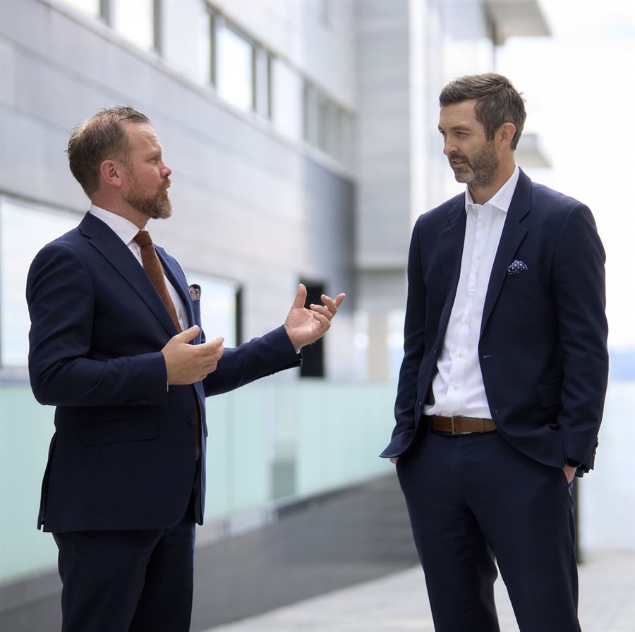To menn står og prater utenfor et bygg