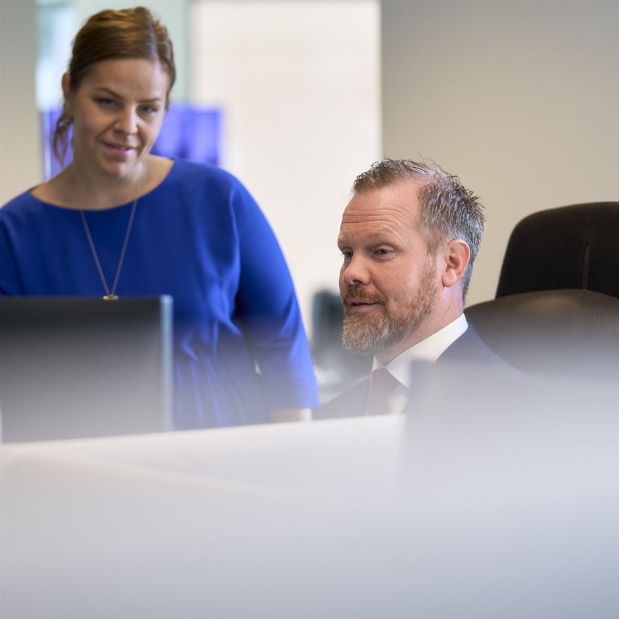 Kvinne og mann står ved PC og prater