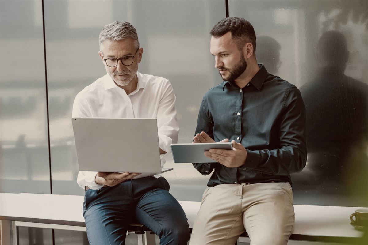 To menn diskuterer og peker på en laptop