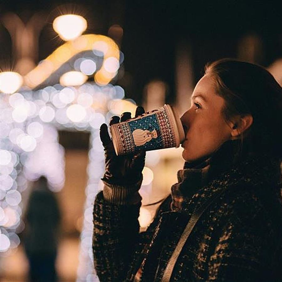 Kvinne drikker fra kopp på julemarked