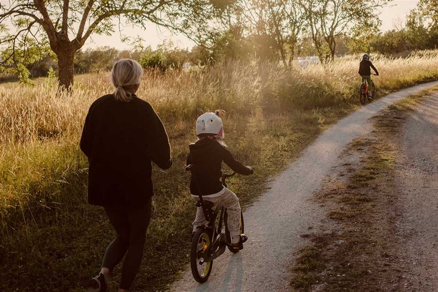 Kvinne som løper ved siden av barn som sykler