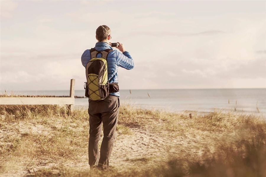 Mann tar bilder på en strand