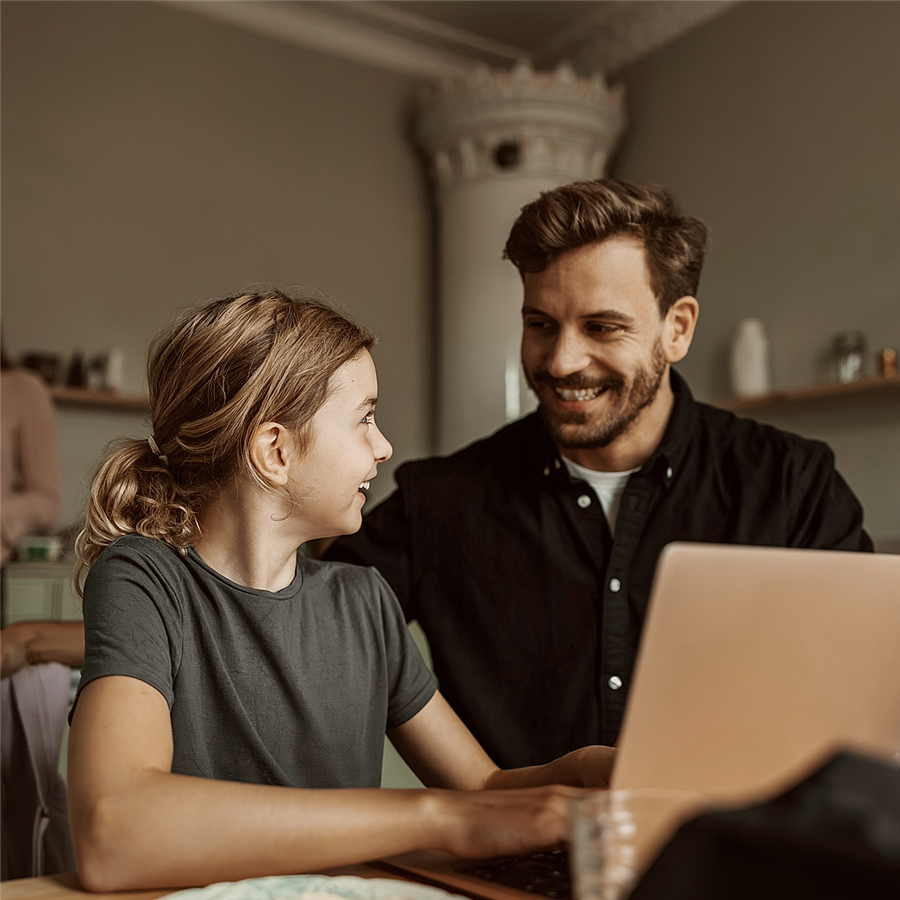 Smiling man talking with daughter using laptop at home