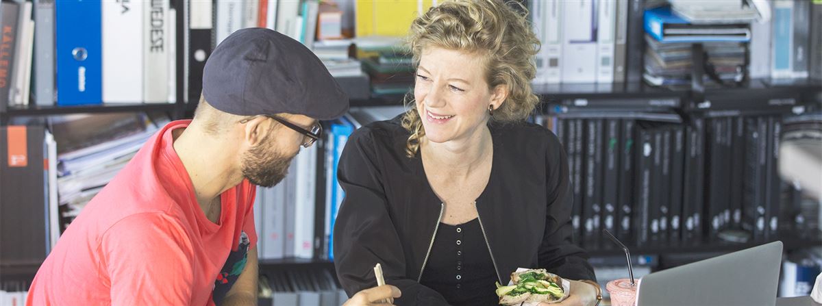 Kvinna och man äter frukost framför dator