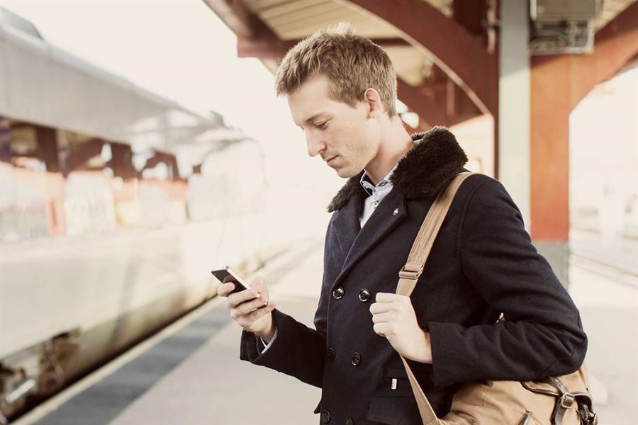 Man using his phone at a train station